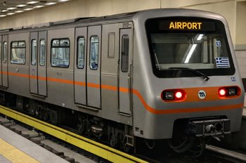 Silver Athens metro train on line 3 with “AIRPORT” displayed, standing in an underground station – the main transport option from the airport to central Athens in 2026.