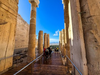 View of the monumental Propylaea columns at the Acropolis in Athens on a sunny day with the city panorama in the background.