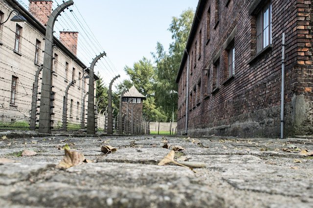 Pathway between brick barracks with barbed wire fences at Auschwitz I in Poland – directions and travel guide from Kraków.