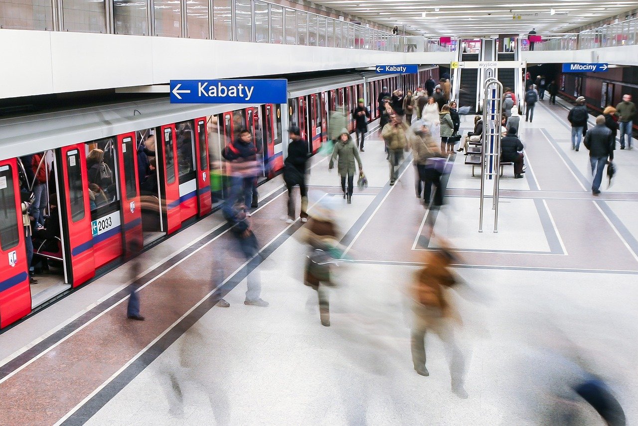Busy Warsaw Metro station platform with a train, illustrating efficient public transport options from Chopin Airport to the city center.