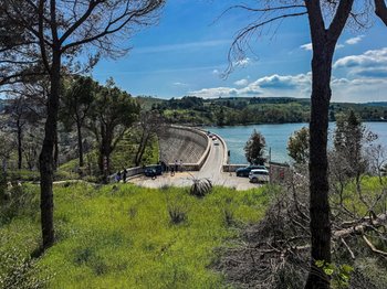 Panoramic view of Lake Marathon and the marble-faced Marathon Dam, a unique day trip destination from Athens, surrounded by lush green hills under a blue sky.
