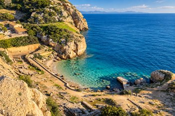 Coastal view of archaeological ruins and turquoise sea during the best time to visit Greece for sightseeing and road trips in the Peloponnese.