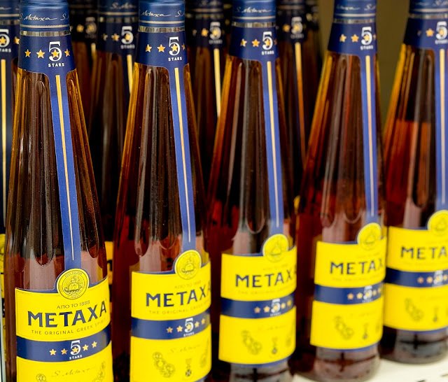 Multiple bottles of Metaxa 5 Stars, a renowned Greek blend of brandy and Muscat wine, on display.