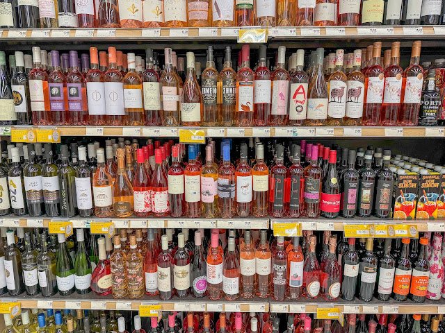 A selection of Greek wine bottles, including red varieties like Agioritiko, displayed on a store shelf.