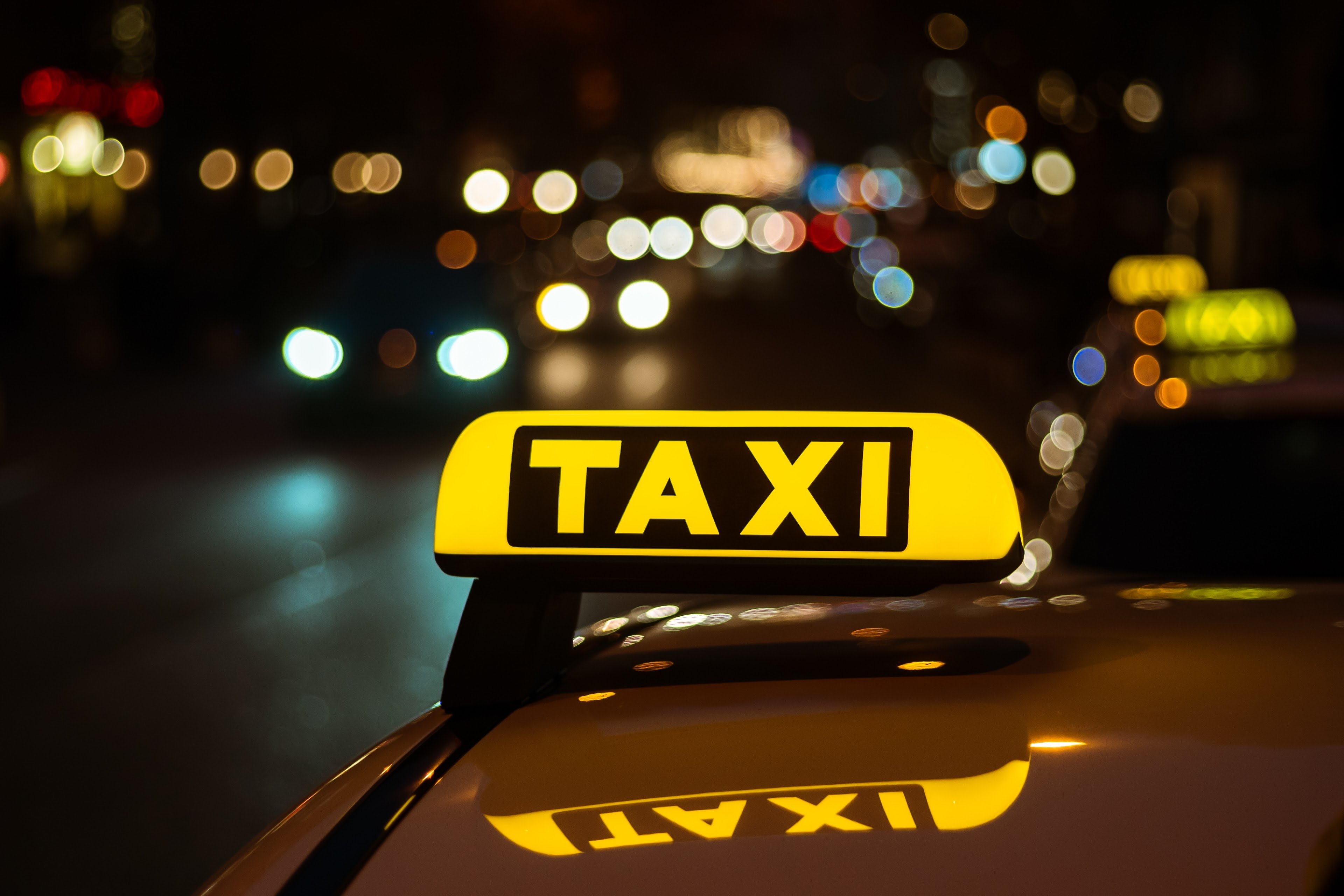 Illuminated yellow taxi sign on a car at night in Warsaw, highlighting official taxi services from Chopin Airport.