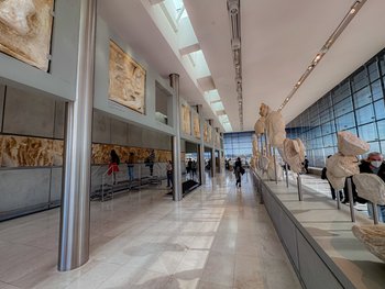Galeria Partenonu w Muzeum Akropolu w Atenach z antycznymi rzeźbami w nowoczesnej, przeszklonej przestrzeni.