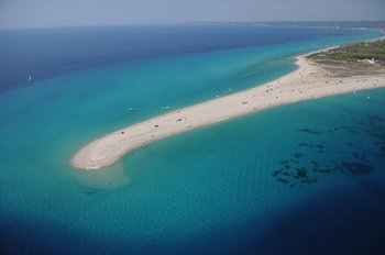 Aerial view of a pristine sandy beach spit extending into the crystal-clear turquoise waters of Halkidiki, Greece, showcasing its stunning coastal beauty and ideal conditions for swimming and relaxation.