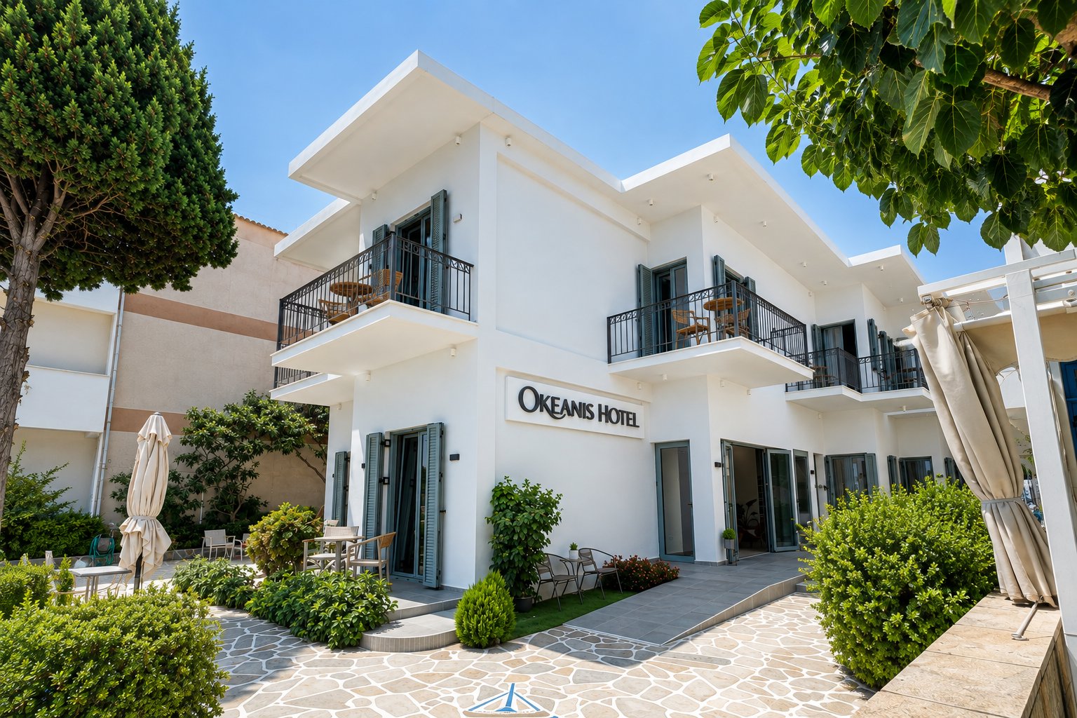 Okeanis Hotel w Tyros, Arkadia, nowoczesny biały budynek z balkonami i zielonym otoczeniem, oferujący noclegi nad morzem.