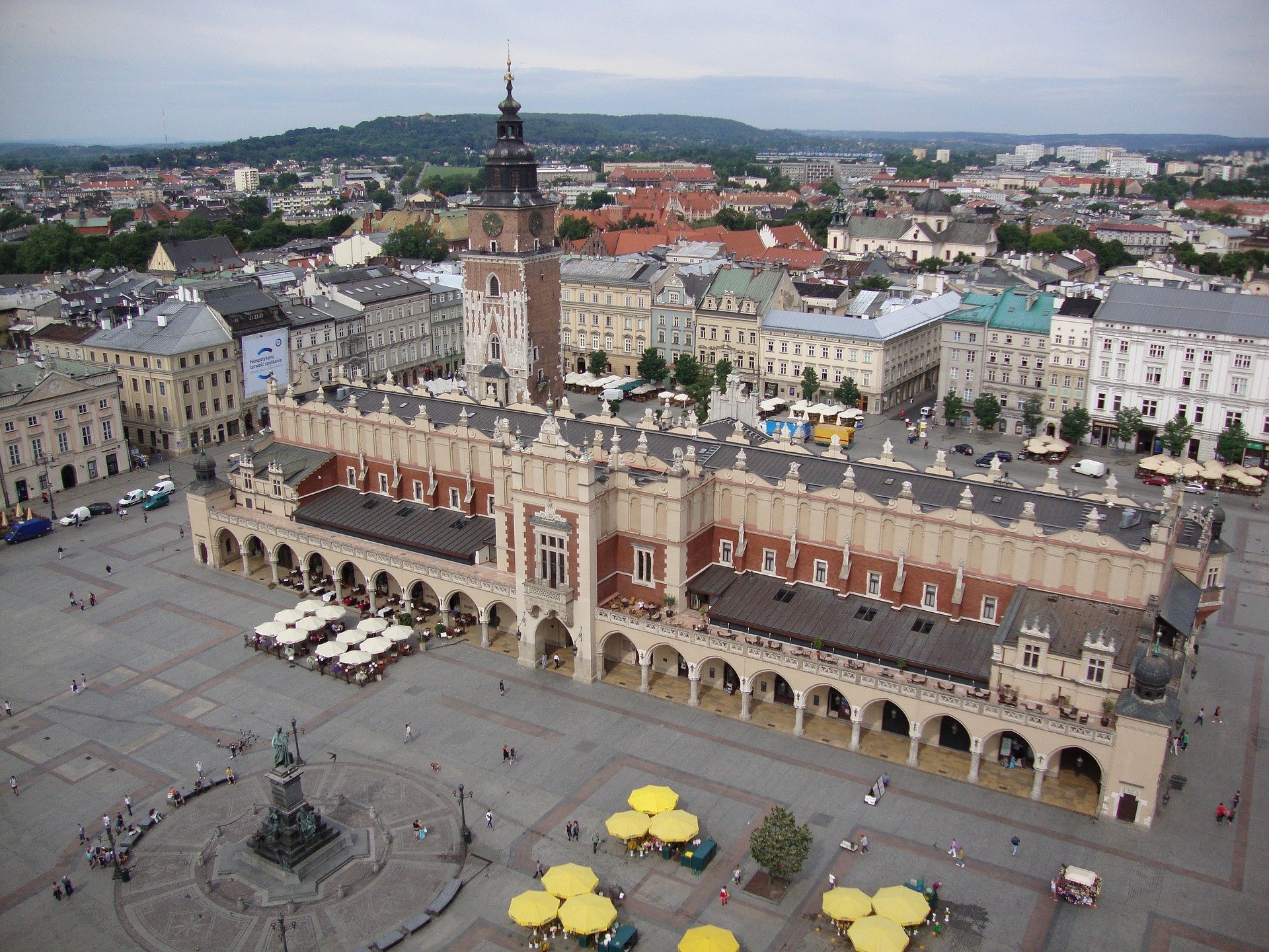 Aerial view of Krakow's Main Market Square with the historic Cloth Hall and Town Hall Tower, showcasing the architectural beauty of the Old Town and its central attractions.