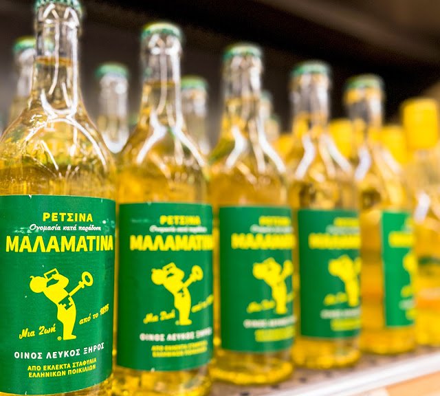 Bottles of Malamatina Retsina, a traditional Greek white wine infused with pine resin, on a shelf.